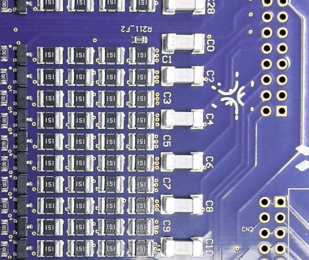 Close-up of a section of the rebuilt board, showing a column of identical chip resistors, a column of ceramic capacitors and the copper pour between them.